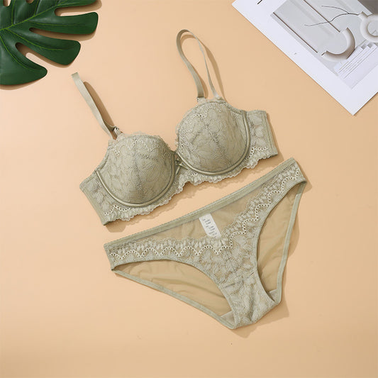 Lace lingerie set on a beige background with a leaf and paper.